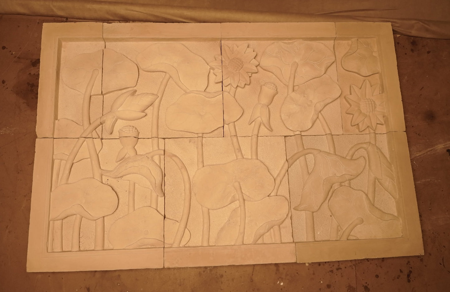 Panel decorativo de pared en piedra caliza con relieve floral natural, estilo boho rústico.